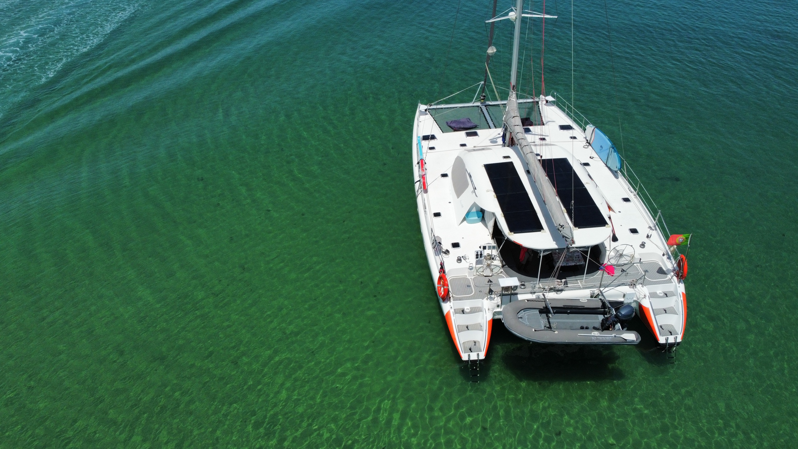 Aerial view of a catamaran boat on clear green water.